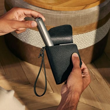Ranka išima Ploom AURA įrenginį iš Jet Black Duo dėklo