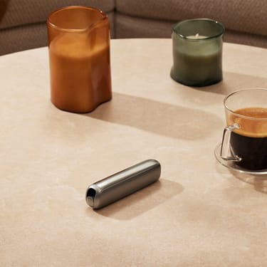Ploom AURA priekinis dangtelis Lunar Silver padėtas ant stalo

