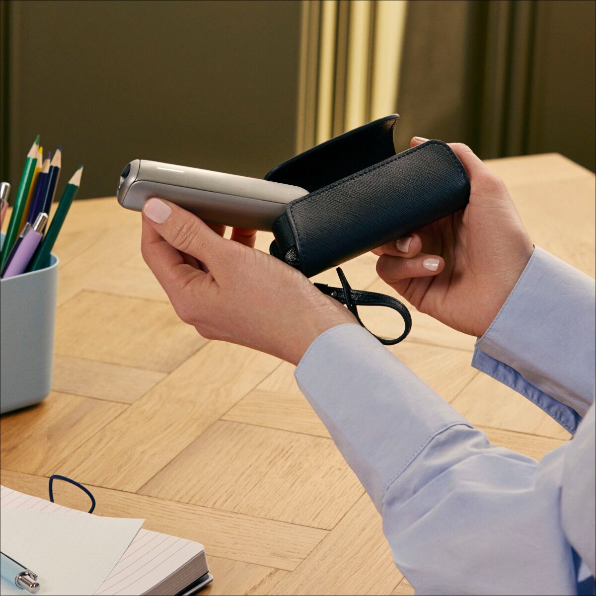 Vartotojas išima Ploom AURA įrenginį iš Jet Black Solo dėklo
